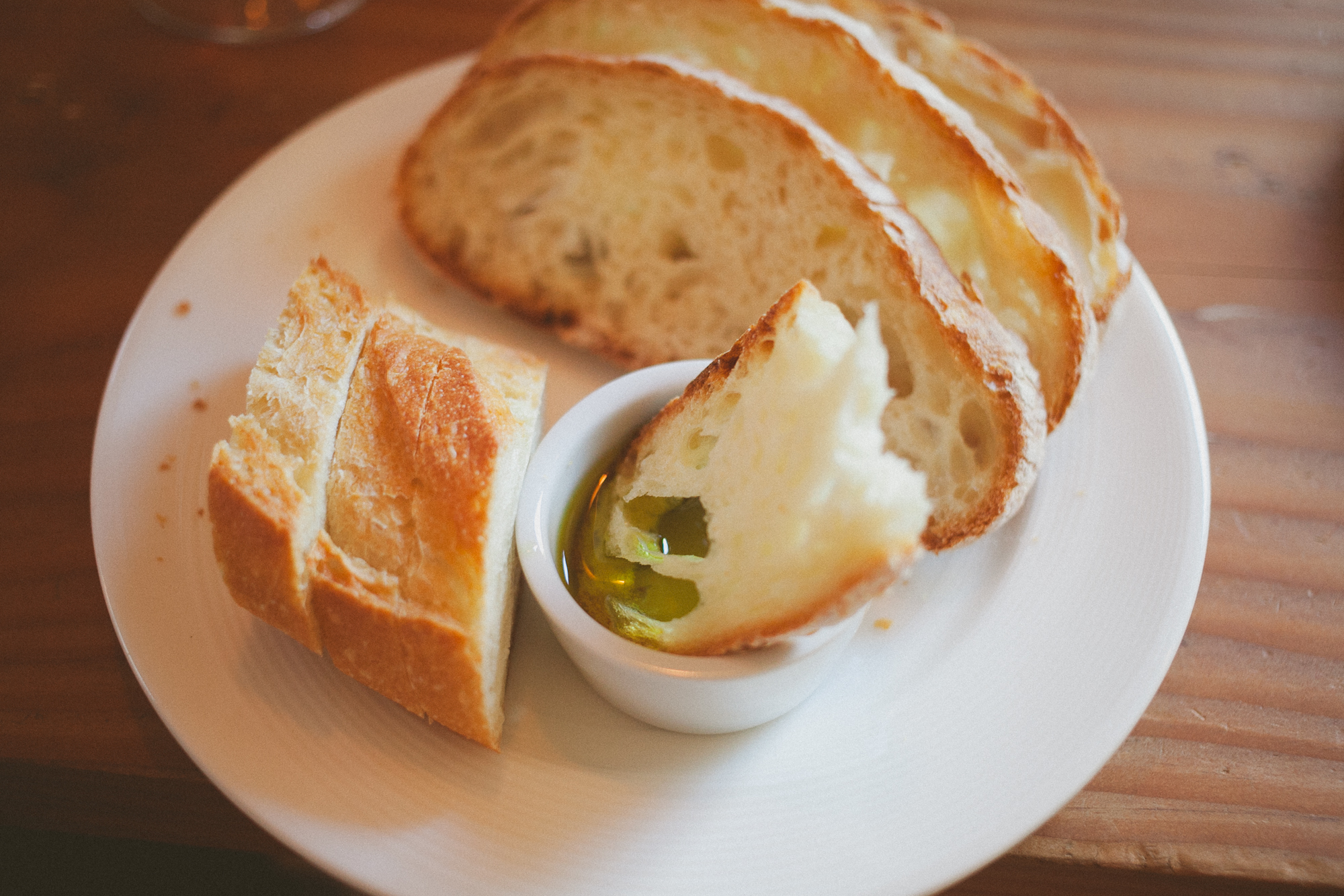 Slices of crusty bread on a white plate with a small dish of olive oil for dipping. Jessica Hill Photography - Wedding Photographer - Oregon