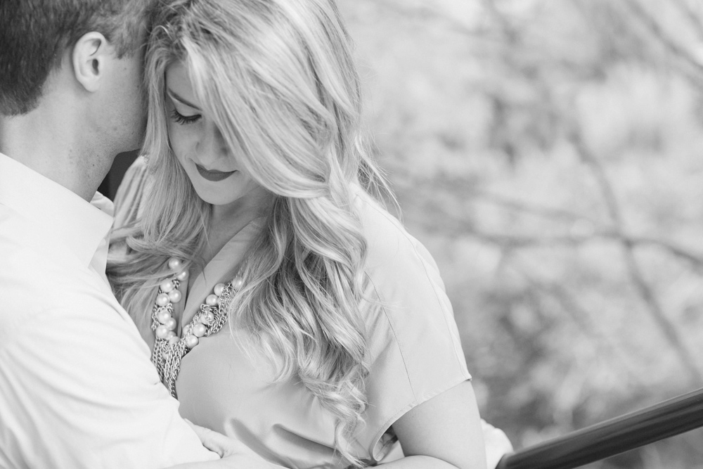 A man and woman are standing outdoors, hugging and smiling at the camera. The background is a blurred field. The photo is in black and white. Jessica Hill Photography - Wedding Photographer - Oregon