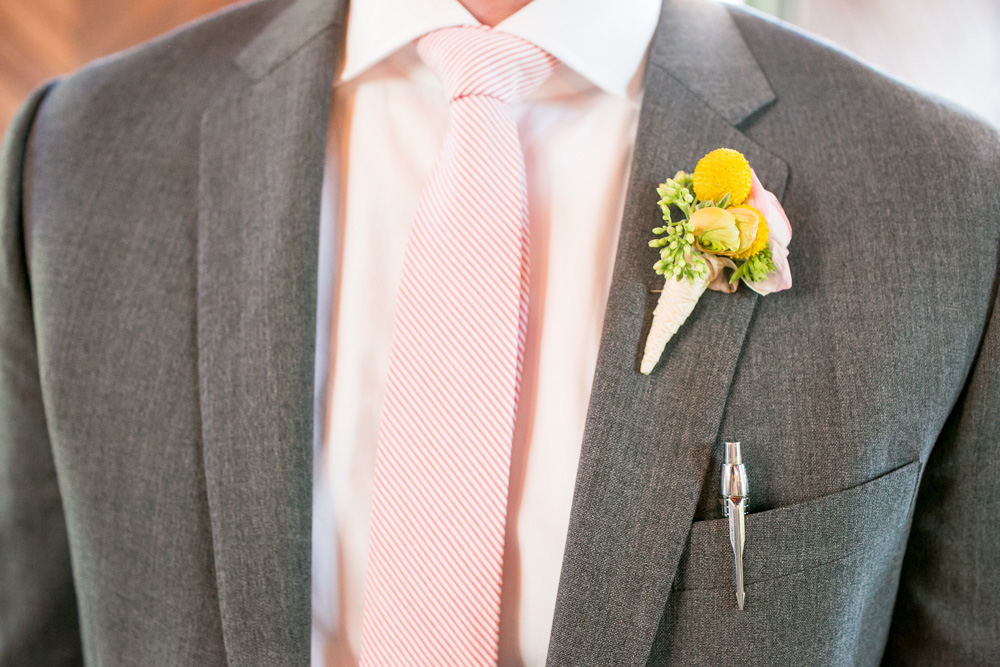 A man in a gray suit with a pink-striped tie, wearing a boutonnière made of yellow and green flowers, and a pen in his chest pocket. Jessica Hill Photography - Wedding Photographer - Oregon