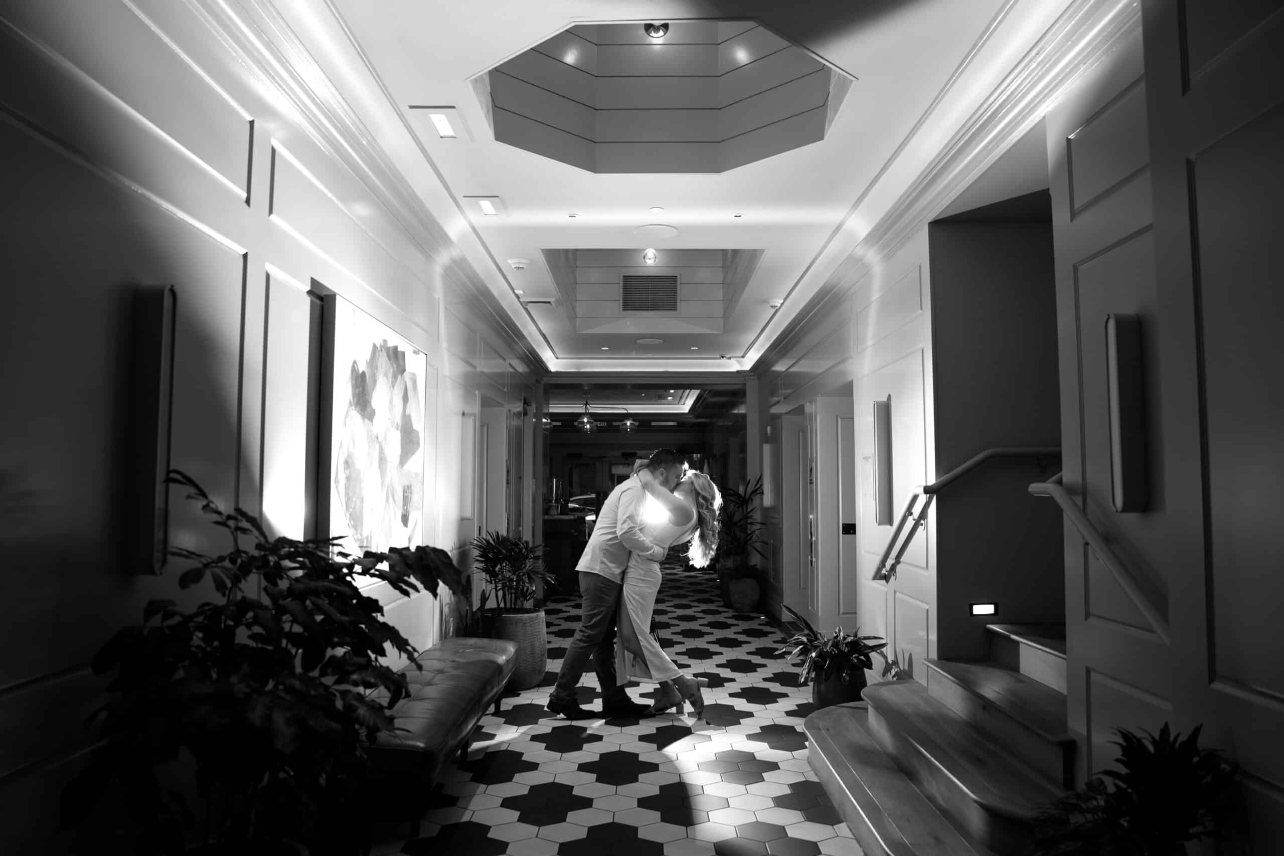 Couple kissing in stylish hallway, black and white photo.