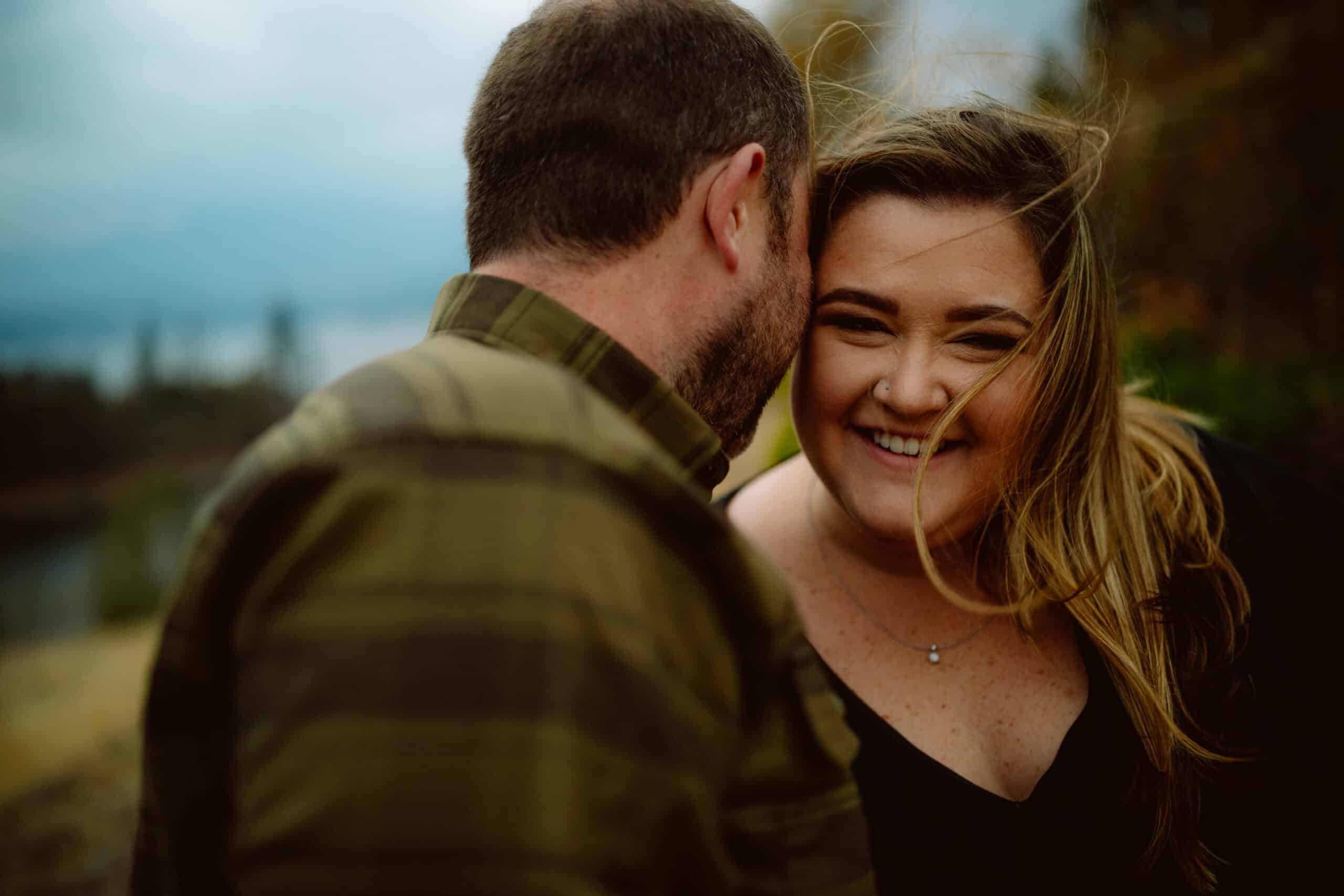 Smiling couple in windy outdoor setting.