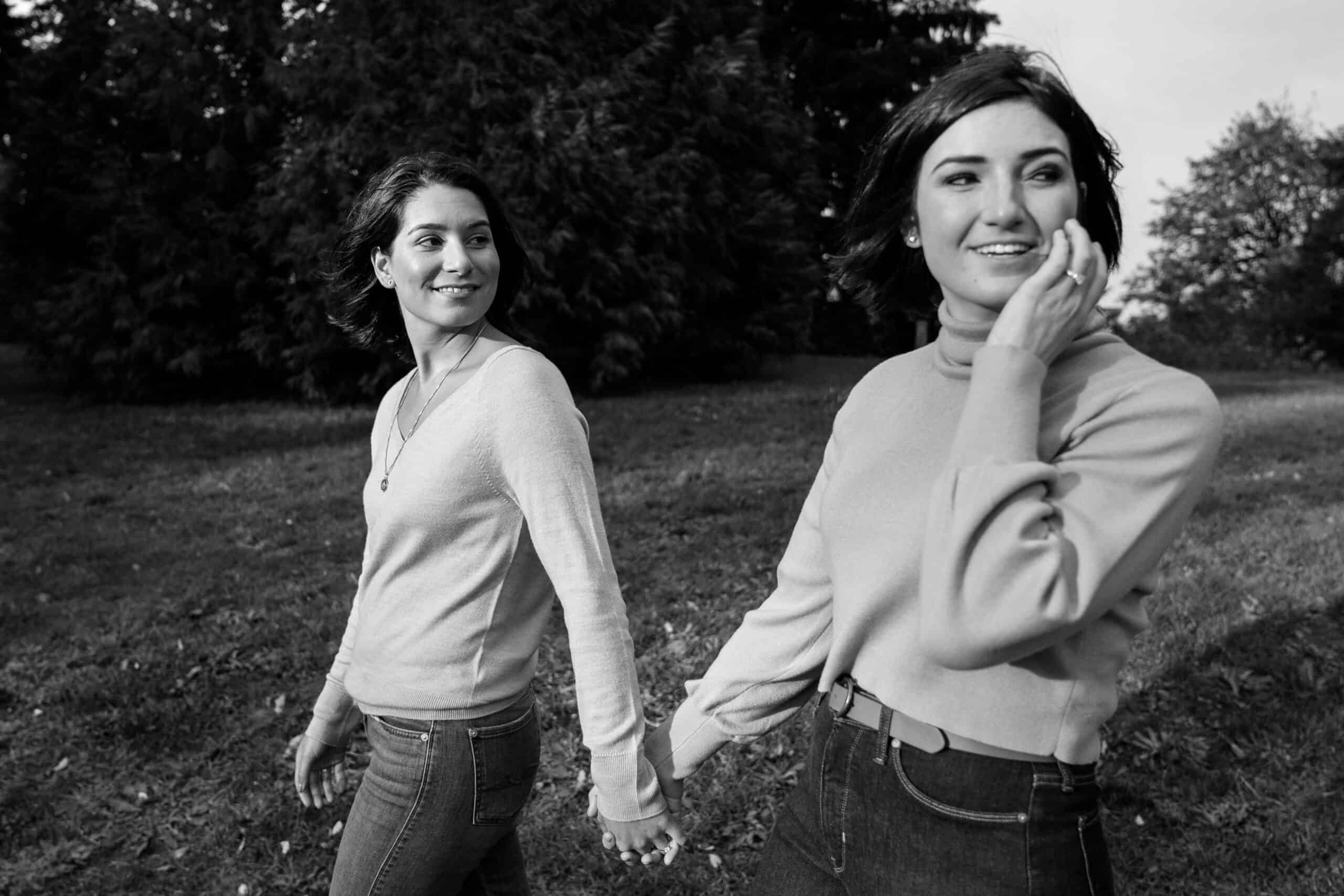 Two women holding hands in a park.