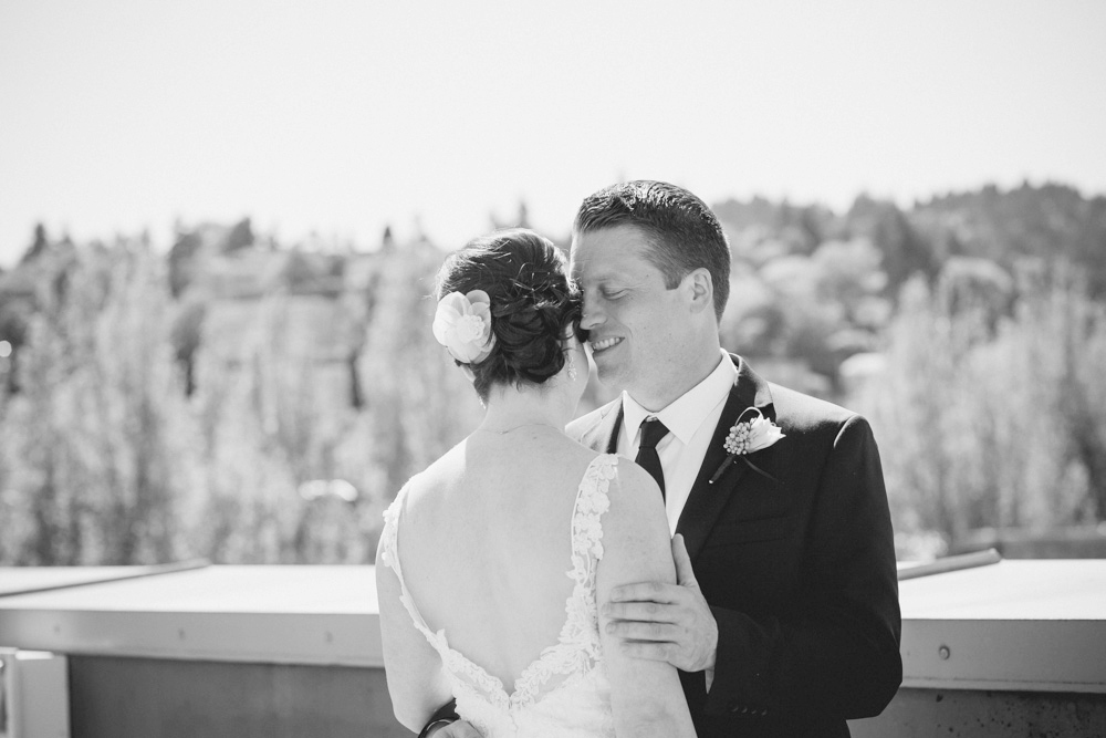 A bride and groom in wedding attire share a dip pose in a bright, elegant room with armchairs and a large movie photo in the background. Jessica Hill Photography - Wedding Photographer - Oregon