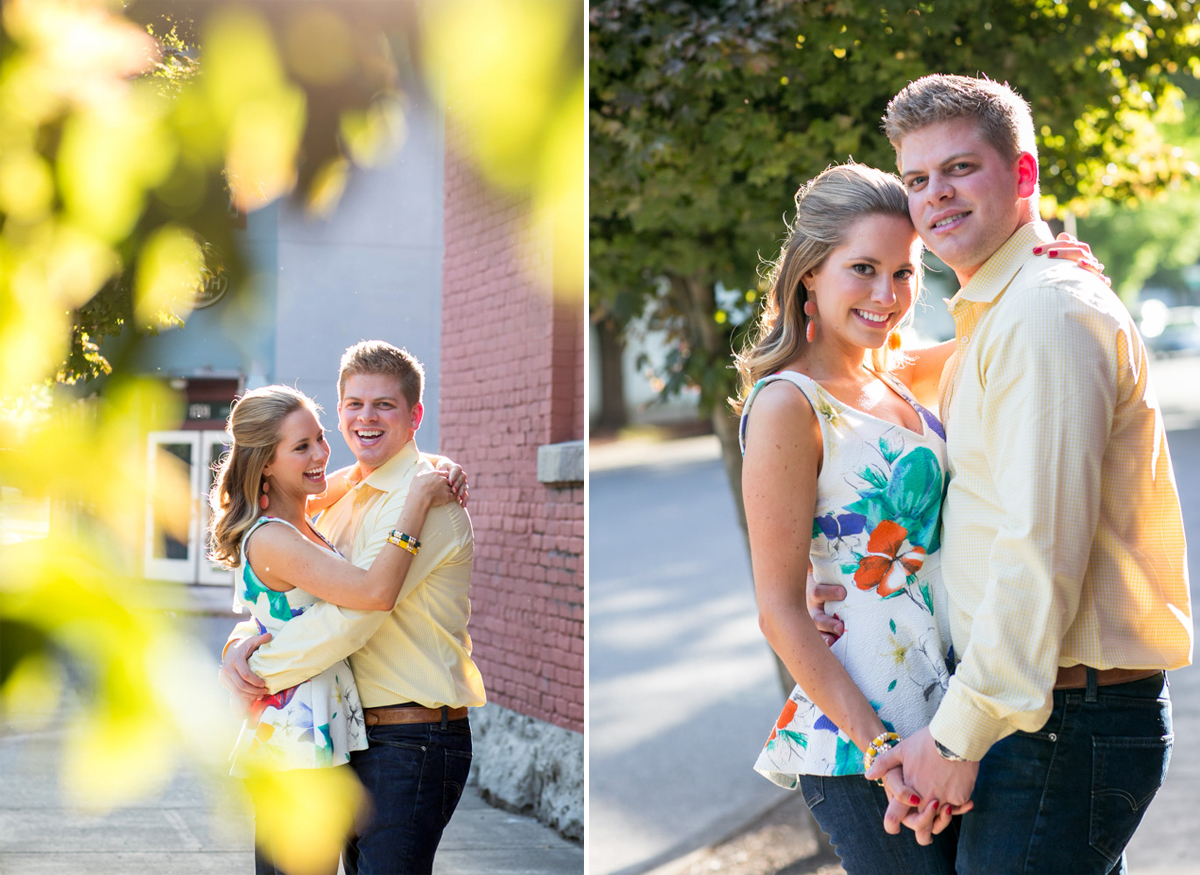 A young couple stands close together outdoors, smiling for the camera in sunny weather. Both are casually dressed, and greenery is visible in the background. Jessica Hill Photography - Wedding Photographer - Oregon