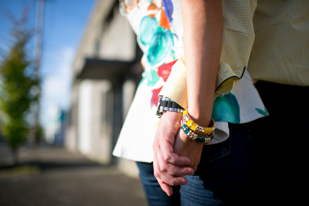 Two people wearing colorful clothing and bracelets hold hands while standing outdoors on a sunny day. Jessica Hill Photography - Wedding Photographer - Oregon