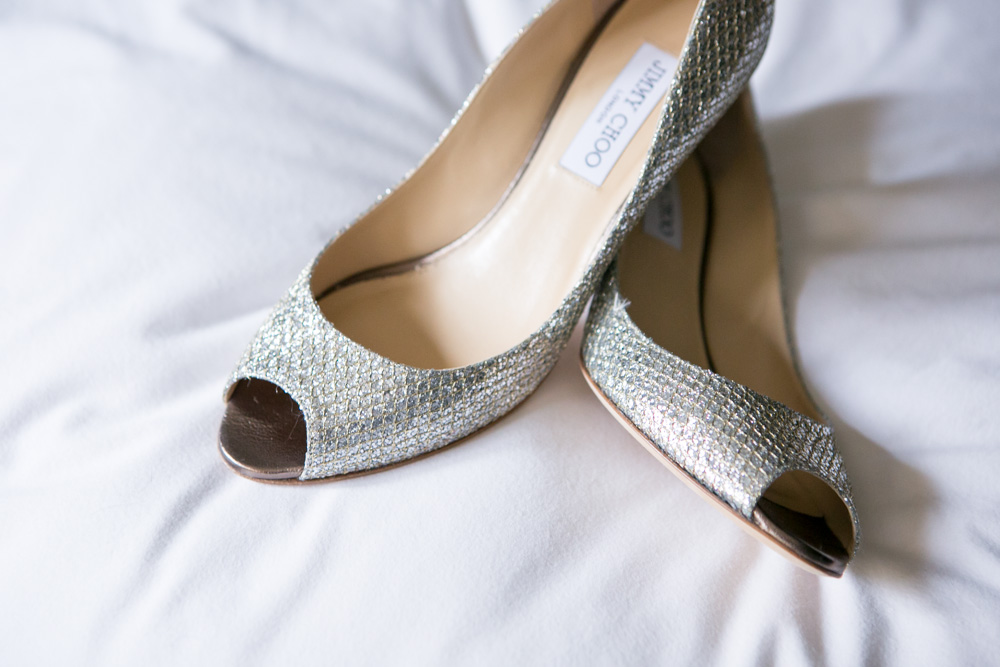 A pair of silver glitter peep-toe high heel shoes rests on a white fabric surface. Jessica Hill Photography - Wedding Photographer - Oregon