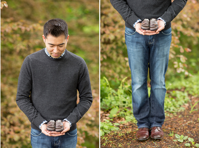A man in a gray sweater and jeans stands outdoors, holding a pair of small brown baby shoes in his hands while looking down at them. Jessica Hill Photography - Wedding Photographer - Oregon