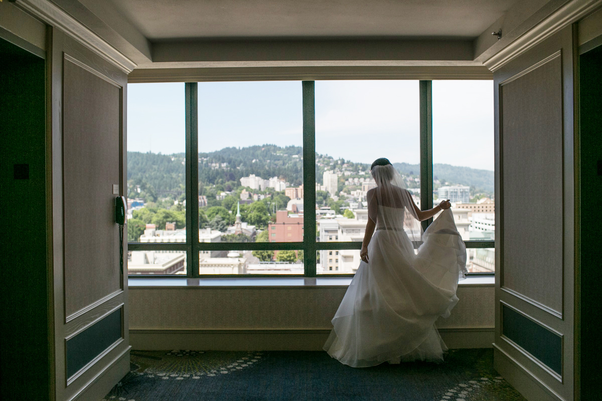 A bride and groom share a dramatic dance dip on a wooden floor, surrounded by seated wedding guests in an elegant, high-ceilinged ballroom with soft, colorful lighting. Jessica Hill Photography - Wedding Photographer - Oregon