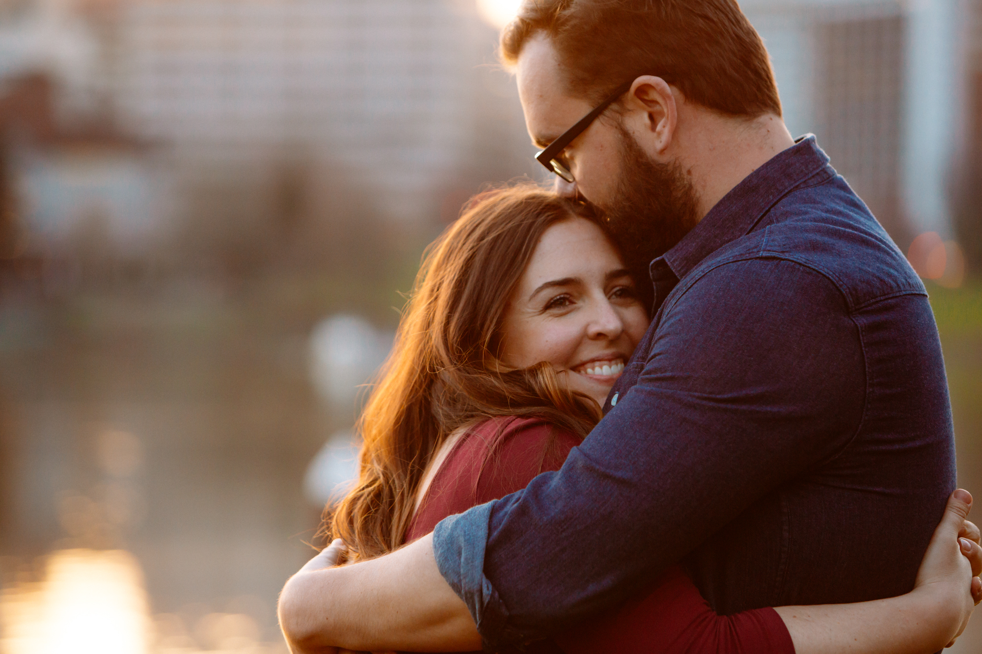 A group of people dressed formally dance together in a warmly lit room with a wooden ceiling and large windows, while a chandelier and string lights hang above them. Shadows are cast on the glass behind them. Jessica Hill Photography - Wedding Photographer - Oregon