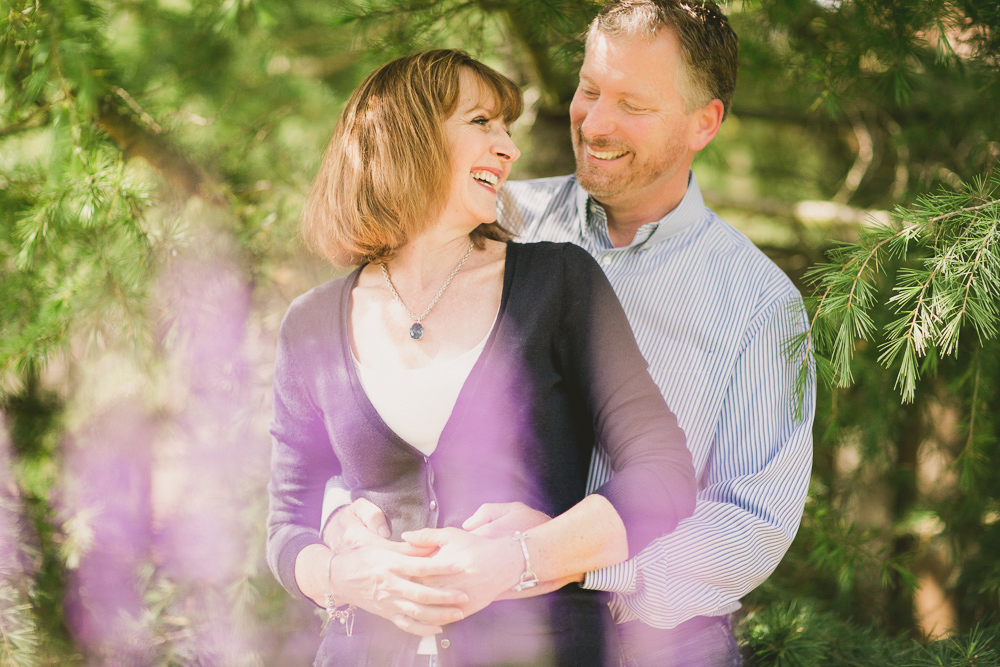 A man and woman stand outdoors among green trees, smiling and embracing each other while looking at each other. Jessica Hill Photography - Wedding Photographer - Oregon