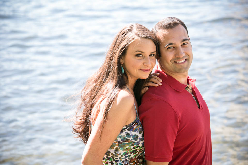 A woman and man standing back to back and smiling in front of a body of water on a sunny day. Jessica Hill Photography - Wedding Photographer - Oregon