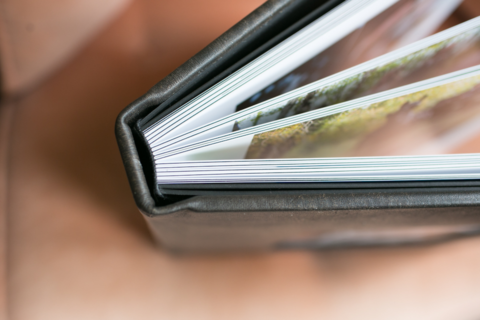 Close-up of the corner of an open photo album with thick, glossy pages and a black cover. Jessica Hill Photography - Wedding Photographer - Oregon