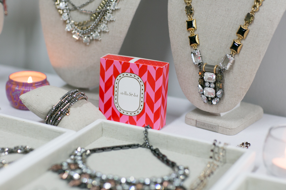 Display of assorted necklaces and bracelets on stands and trays, with a red patterned box and lit candles in the background. Jessica Hill Photography - Wedding Photographer - Oregon
