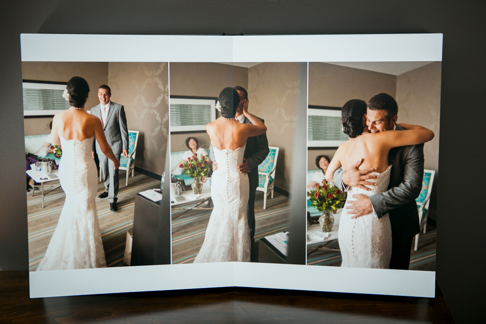 A wedding album open to pages showing a bride and groom embracing in a room, with a seated woman in the background. Jessica Hill Photography - Wedding Photographer - Oregon