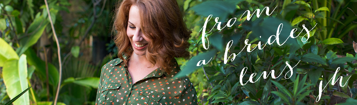 A woman with shoulder-length auburn hair wearing a green polka-dot shirt stands among lush green plants, smiling and looking down. Text overlay reads "from a bride's lens jh. Jessica Hill Photography - Wedding Photographer - Oregon