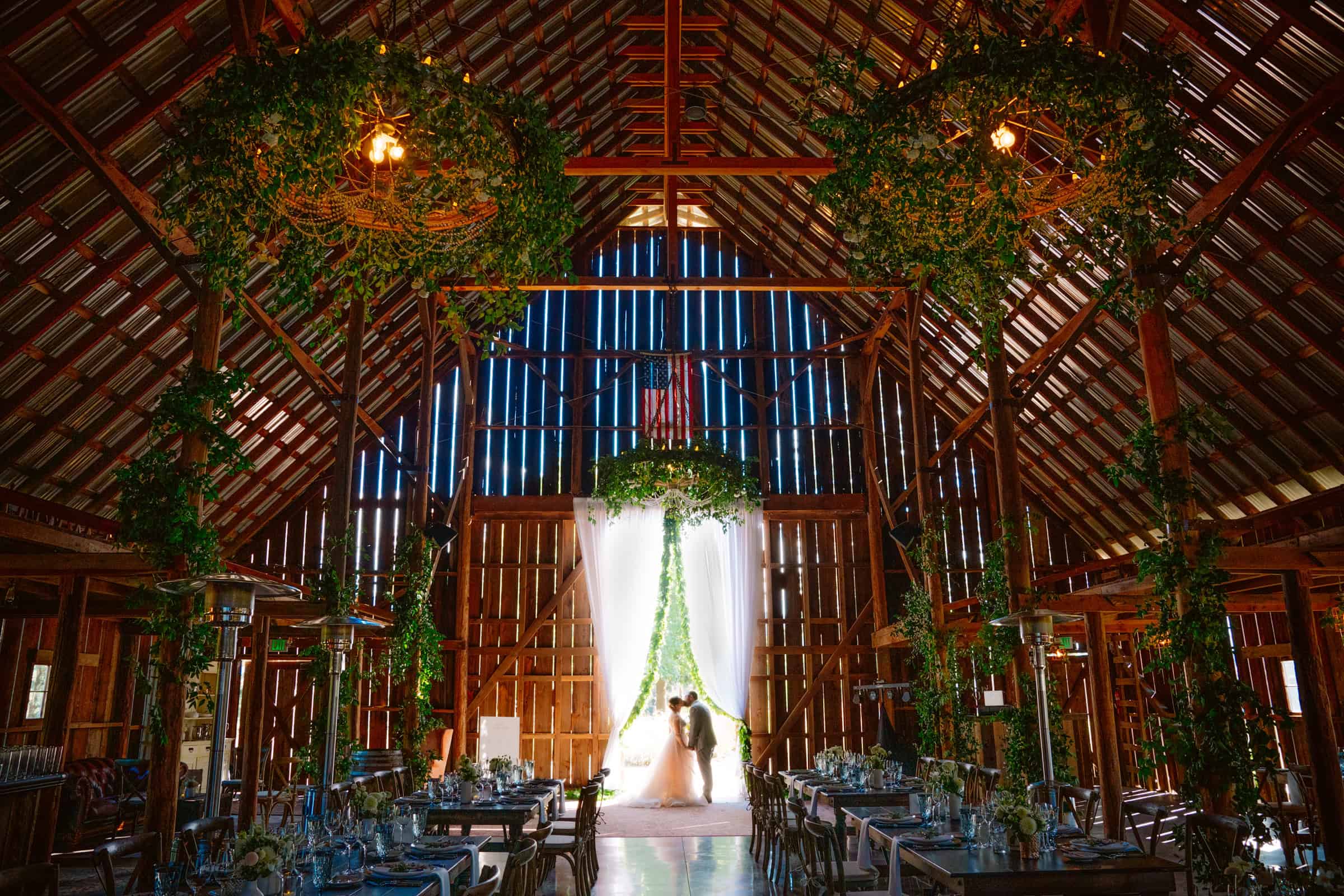 Wedding in rustic, decorated barn with dramatic lighting.