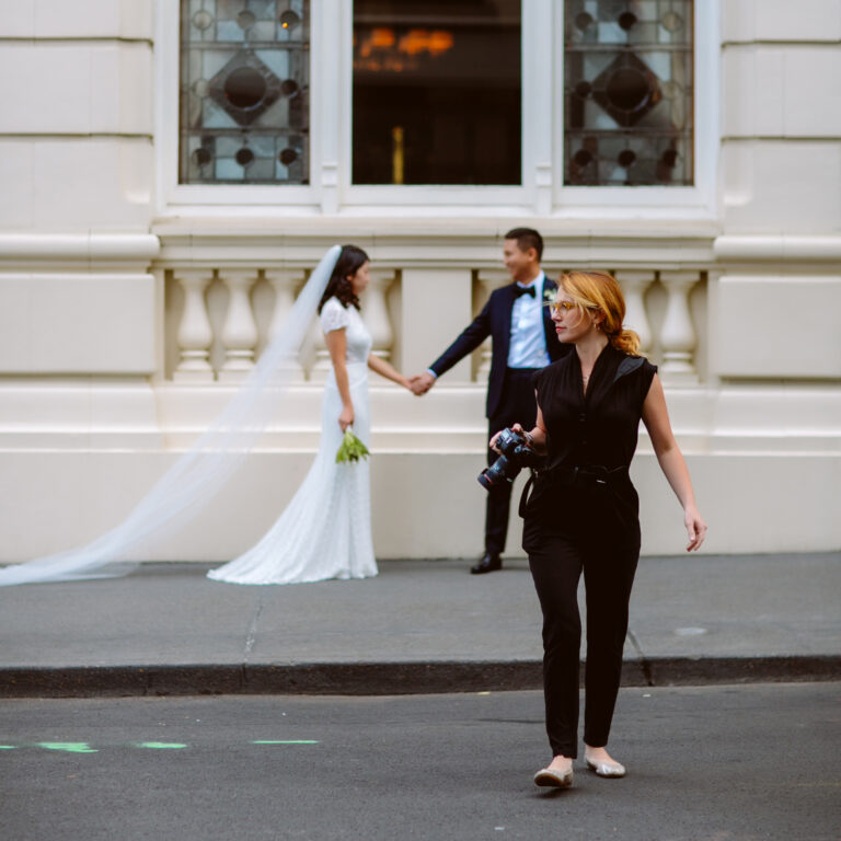 Photographer at wedding with bride and groom outdoors.