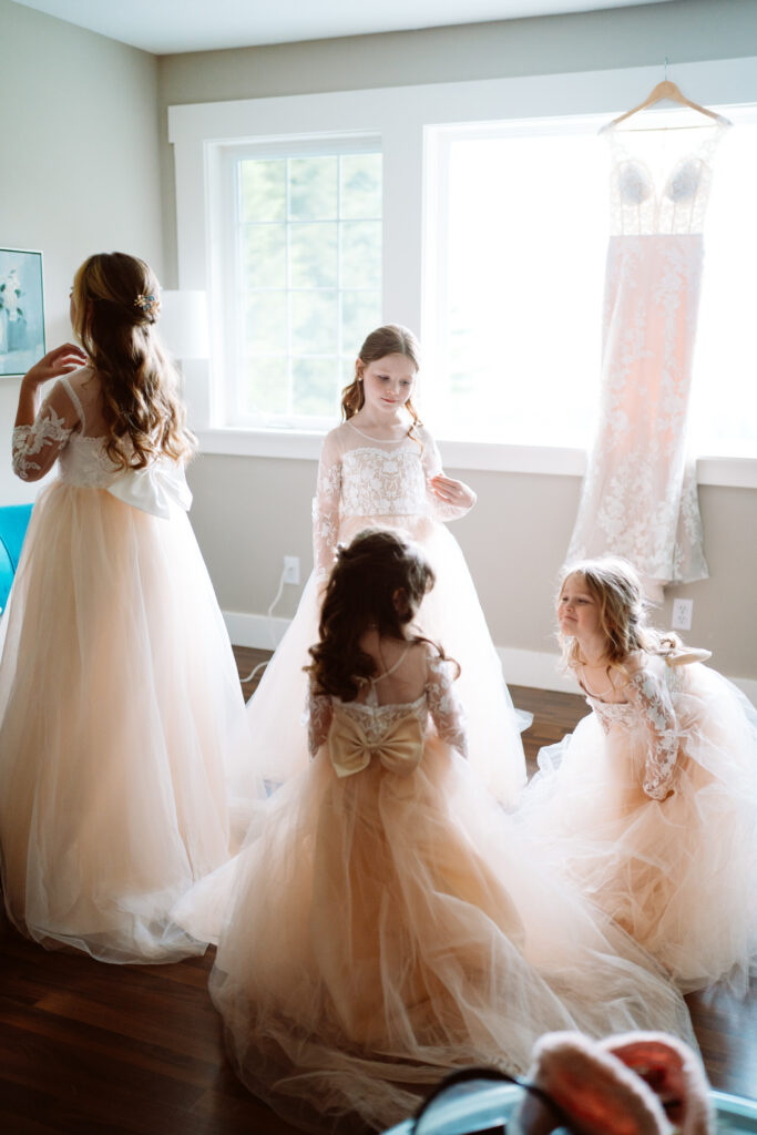 Young girls in flower girl dresses near bridal gown.