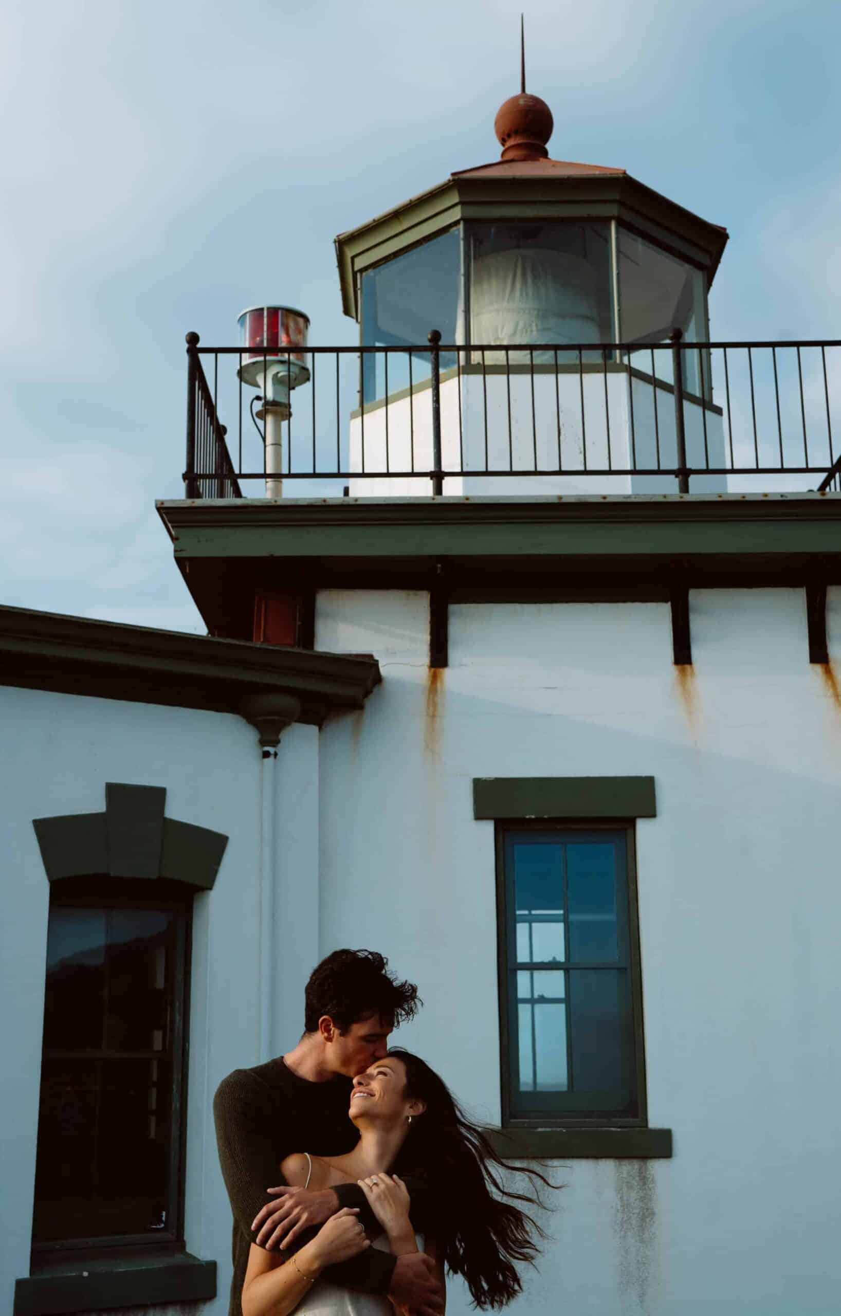 Couple embracing near a lighthouse.