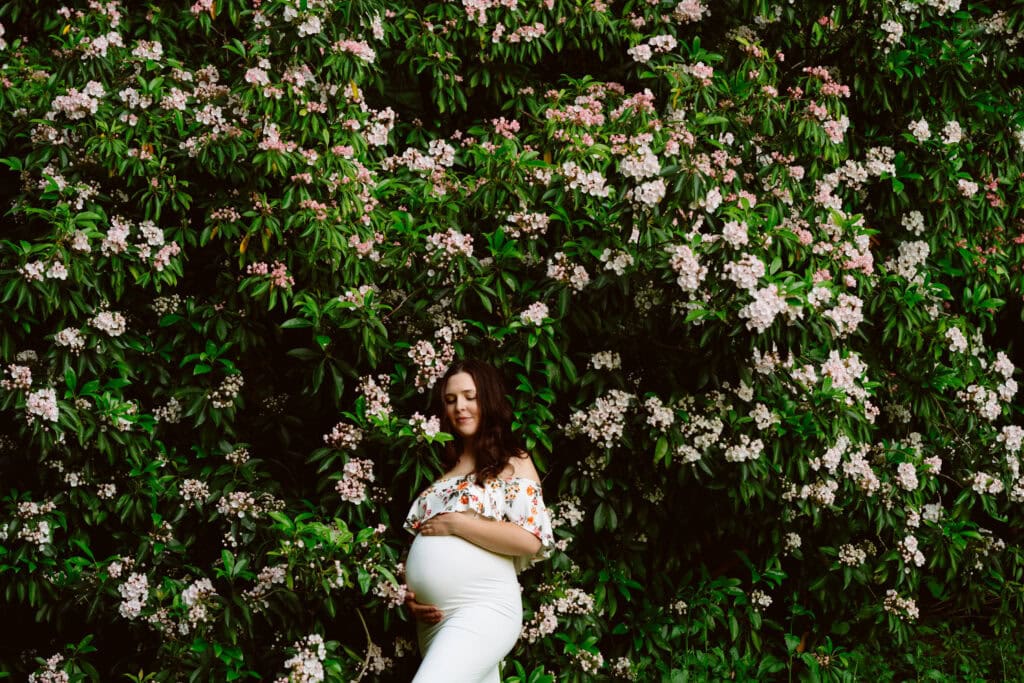 Pregnant woman in front of flowering bushes