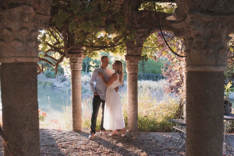 Couple embraced under stone gazebo.