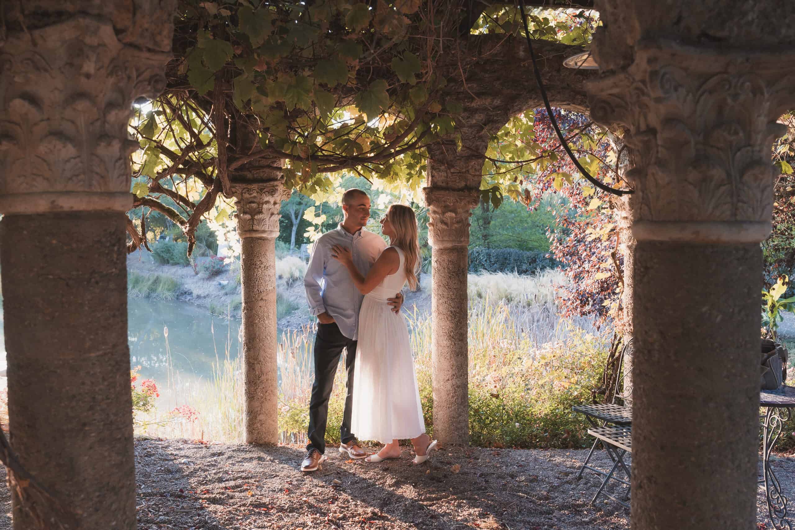 Couple embraced under stone gazebo.