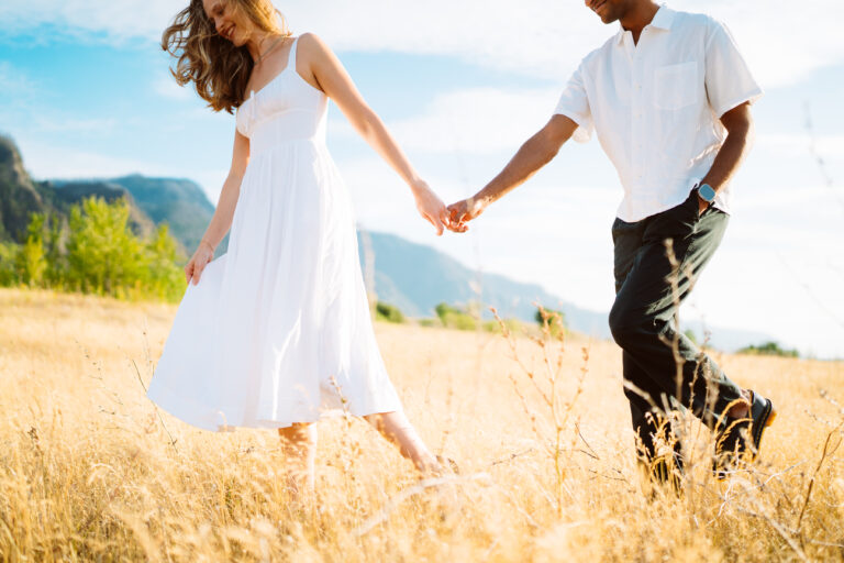 Couple holding hands in golden field at sunset